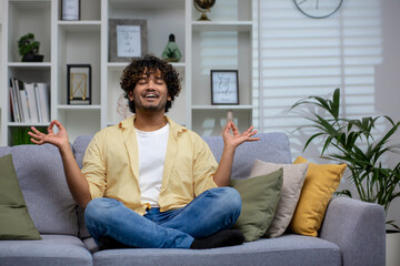 A young adult sits cross-legged on a couch, meditating in a peaceful living room setting, embodying tranquility and mindfulness.