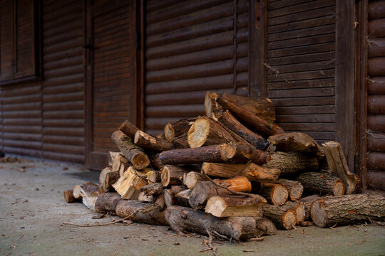 A pile of firewood lies near a wooden house
