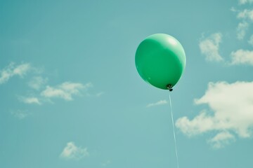 Obraz premium Vibrant green balloon representing mental health awareness floating against a soft blue sky creating a hopeful message of exploration and understanding