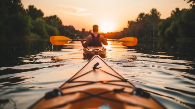 Man kayaking at sunset on calm sea, rear view of paddler in kayak enjoying peaceful waters