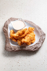 Fried chicken with breaded white sauce in a stone bowl on a white table