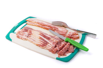 a half pound of sliced smoked bacon on a cutting board with a kitchen knife and a fork isolated on white