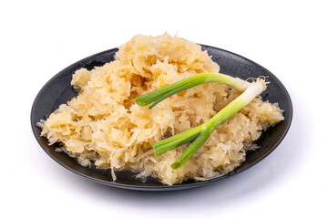 A heap of sauerkraut with green onion shallots on a black plate isolated on white