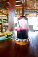 Refreshing berry mojito cocktail on the table with a plate of snack