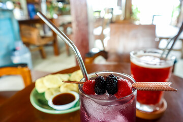 Refreshing berry mojito cocktail on the table with a plate of snack