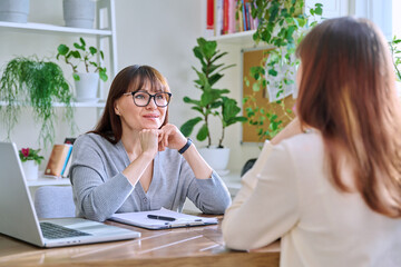 Middle-aged female psychologist, counselor working with young woman patient