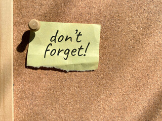 Notice reminder don't forget on bulletin board background. Stock photo.