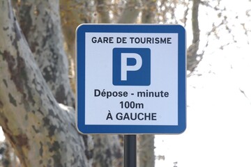 Panneau de signalisation : parking gare de tourisme, dépose-minute à 100 mètres à gauche.