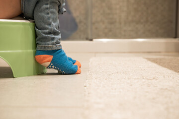 Small child sitting on plastic potty in bathroom. Concept of acquiring physiological skills. Close...