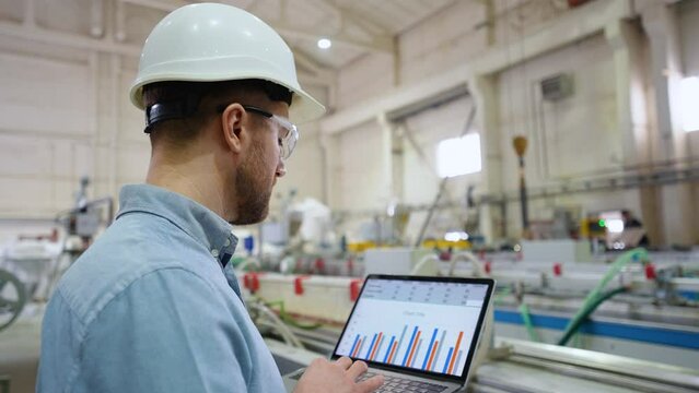 Industrial engineer programmer checking the production line with laptop at windows factory. Factory for aluminum and PVC windows and doors production