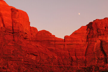 The moon and the sunset-lit sandstone cliffs of Monument Valley Navajo Tribal Park, Utah - Arizona state border, USA.