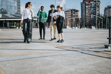 Obraz premium Diverse group of business associates engaged in a strategy meeting outside, with urban architecture in the background.