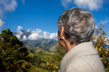 Senior woman tourist looking at the amazing landscapes of the Central Ranges on the ascent to the High of Letters between the cities of Fresno and Manizales in Colombia