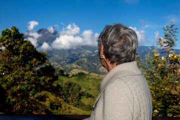 Senior woman tourist looking at the amazing landscapes of the Central Ranges on the ascent to the High of Letters between the cities of Fresno and Manizales in Colombia
