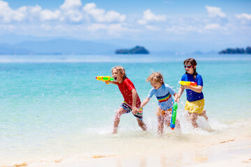 Child with toy water gun. Kids vacation beach fun. - obrazy, fototapety, plakaty