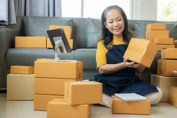 Happy mature businesswoman, small business owner in warehouse office There are parcel boxes piled...
