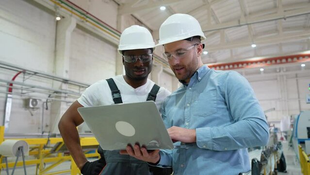 Supervisor and manual worker using laptop in heavy industry