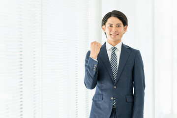 オフィスでガッツポーズする若いアジア人男性ビジネスマン（やりがい・就職・就活・転職・成功）
