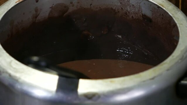 POV: bean stew. Person mixing black beans in a pot, close-up shot. Steaming pot of beans on the stove. Preparing baked beans. Steaming pot of feijoada (bean stew). Cooking beans. Steamy food.