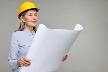 Architect in hard hat with draft on grey background