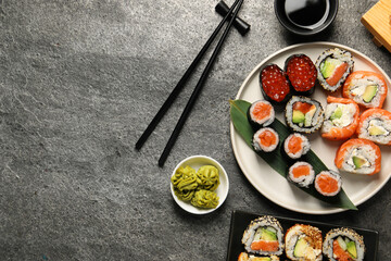 Flat lay composition with delicious sushi rolls on dark grey table. Space for text