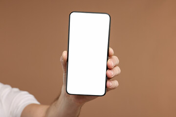 Man showing smartphone on light brown background, closeup. Mockup for design
