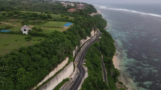 Aerial view, cliffside asphalt road and sea located on Tanah Barak beach, Bali island, Indonesia.