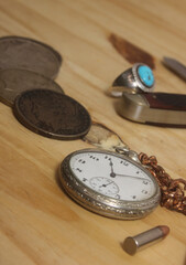 Pocket Watch With Silver Coins and Knife on Wooden Table