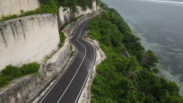Aerial view, cliffside asphalt road and sea located on Tanah Barak beach, Bali island, Indonesia.