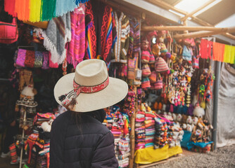 Young woman traveler in hat walks through market typical city in Cusco, Peru. Copy space