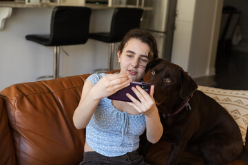 Teen Girl and Chocolate Labrador Taking a Selfie. A smiling young girl takes a selfie with her...