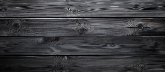 A closeup of a rectangular black hardwood table with grey tints and shades. The parallel planks and...