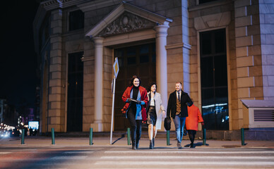 A dynamic scene of four friends casually strolling through a brightly lit city street at night, evoking feelings of freedom and companionship.