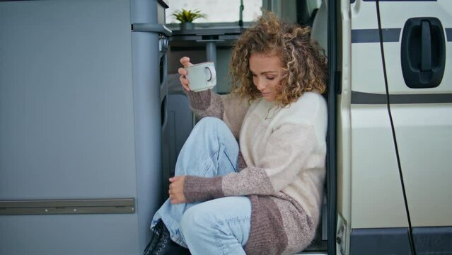 Dreamy lady resting tea cup sitting trailer stairs closeup. Attractive traveller