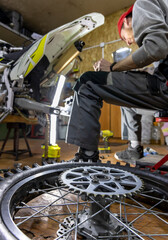 The master is busy repairing a mountain bike in the garage. wheel, chain, tire, engine and other elements
