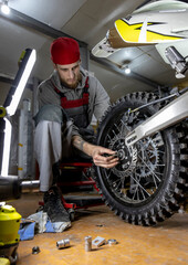Fototapeta na wymiar The master is busy repairing a mountain bike in the garage. wheel, chain, tire, engine and other elements 
