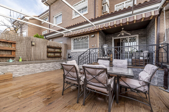 a terrace with smooth metal furniture and wicker dividers for greater privacy with stairs with black painted metal wrought iron railings in a single-family home with folded awnings
