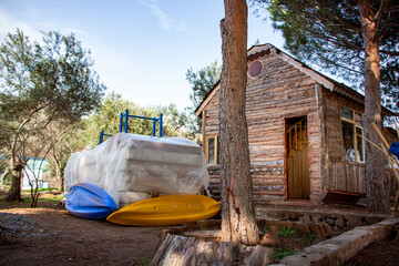 Abandoned wooden house with kayaks on the beach in Turkey. Blue and yellow kayak on the ground in...