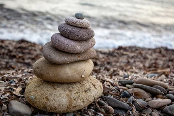 Foto auf Glas Stack of zen stones on the beach. Zen and harmony concept. Pyramid of pebbles on the beach at sunset. Stack of zen stones on the seashore. Zen concept © Caneritir