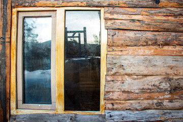Window of a log house in the winter in the village. Wooden house in village.