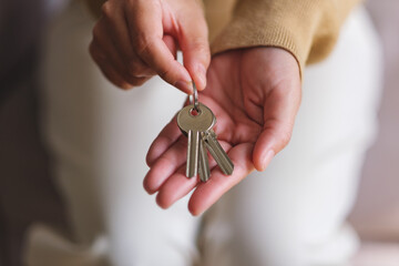 Closeup image of a woman holding and giving the keys for real estate concept - obrazy, fototapety, plakaty