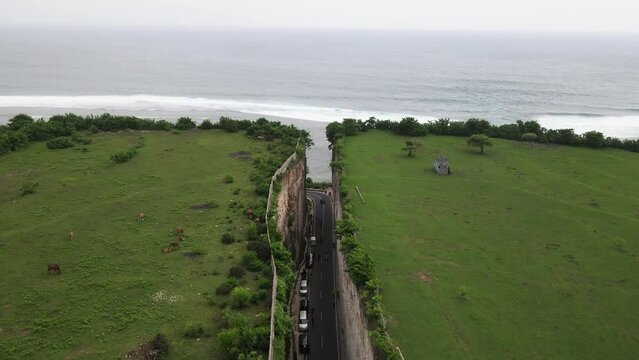 Aerial view, asphalt road that penetrates the cliffs of Tanah Barak on the island of Bali to connect to Pandawa beach.