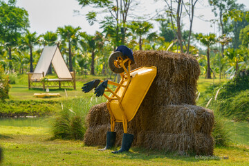 A small yellow cement cart leaned against a pile of hay.