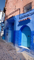 Blue, wooden door in a blue wall in the medina, in Chefchaouen, Morocco