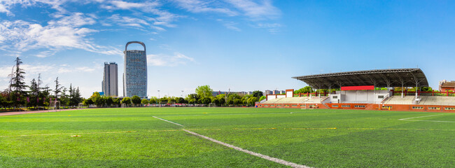 The unmanned outdoor football stadium is located on the university campus, with clear skies