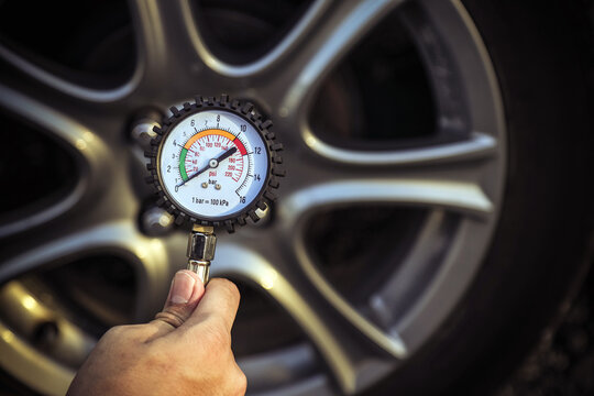 Hand car mechanic holding car tire pressure check equipment tool to checking low tire pressure inflating tires to or refill or air inflate to safety and car care service maintenance inspection.