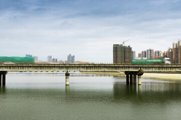 From the riverbank in the city, you can see the highway bridges on the river and the towering buildings in the distance