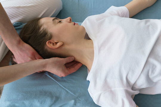young masseuse does a Thai massage on the floor massaging her neck and shoulders