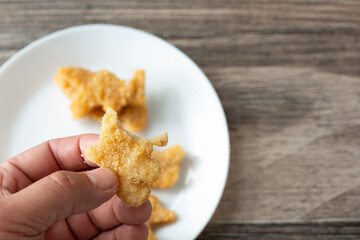 A view of a hand holding a half-eaten dino nugget.