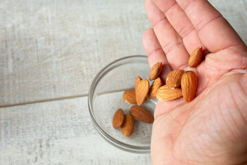 A view of a hand dropping almonds into a glass condiment cup.